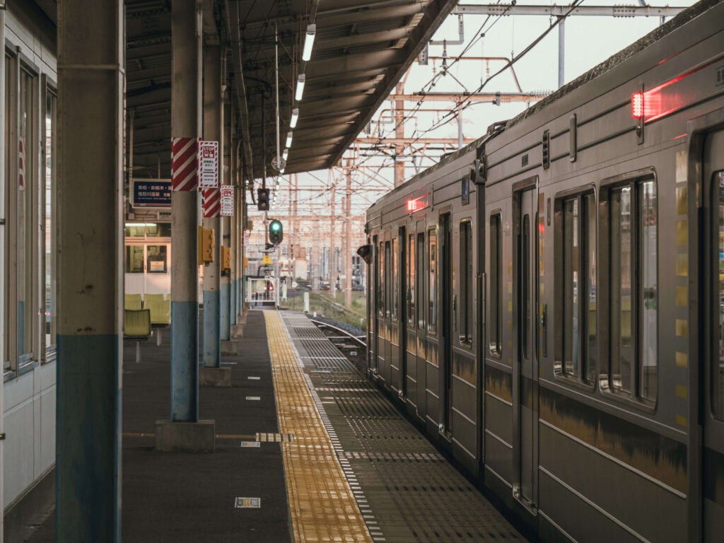 Un quai de gare au Japon avec un train à quai, prêt à partir, dans une ambiance calme et lumineuse en fin de journée.