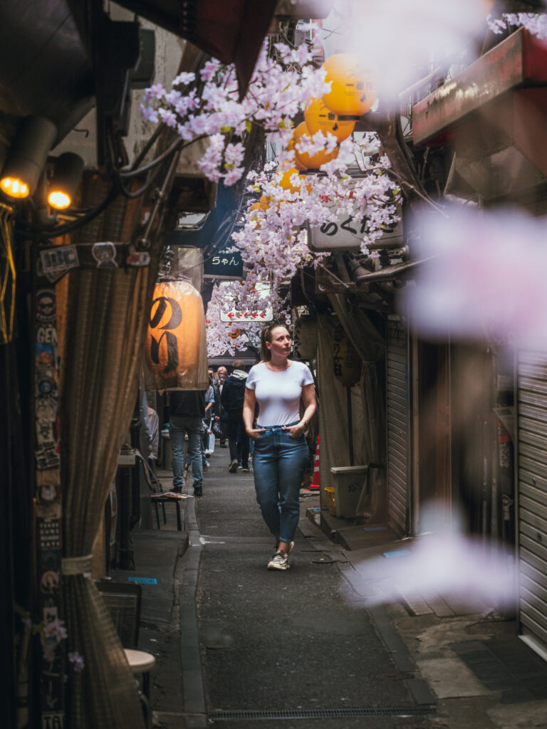 Sandie marchant dans une ruelle typique de Tokyo décorée de cerisiers en fleurs pendant le printemps au Japon